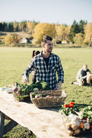 Mittlerer Erwachsener, der Bio-Gemüse auf einem Tisch auf dem Bauernmarkt verkauft, lizenzfreies Stockfoto