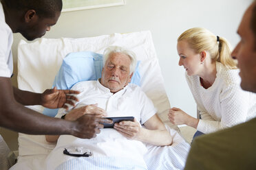 Male nurse showing digital tablet to senior man and couple at hospital ward - MASF01647