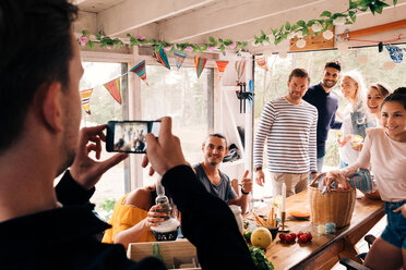 Mann fotografiert Freunde mit Smartphone in Hütte - MASF01665