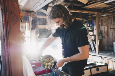 Man preparing food in kitchen at holiday villa on sunny day - MASF01673