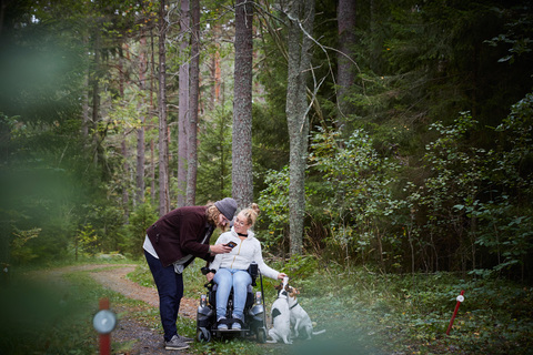 Männlicher Hausmeister mit behinderter Frau, die im Wald ein Mobiltelefon benutzt, lizenzfreies Stockfoto