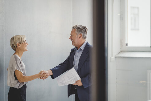 Mature businessman and businesswoman shaking hands in new office - MASF01707