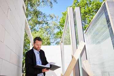 Niedriger Blickwinkel eines Architekten, der ein Dokument liest, während er auf der Baustelle steht - MASF01721