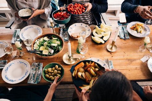 Hochformatige Ansicht von Männern und Frauen beim gemeinsamen Essen in einer Hütte - MASF01745