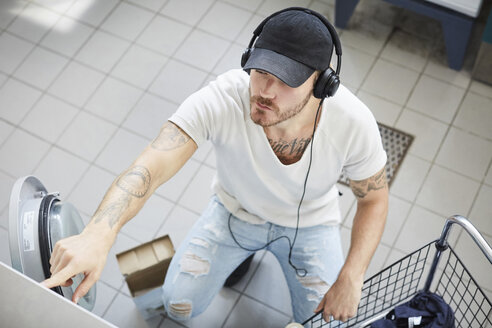 Blick von oben auf einen jungen Studenten, der beim Wäschewaschen Musik hört - MASF01759