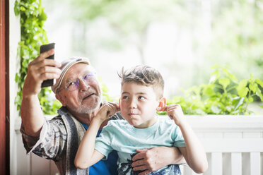 Grandfather taking selfie with grandson in porch - MASF01797