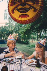 Fröhliches Geschwisterpaar stößt bei einer Gartenparty mit Getränken an - MASF01801