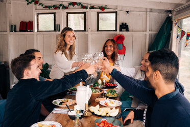 Happy men and women toasting wineglasses in cottage - MASF01811