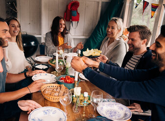 Glücklicher Mann zündet eine Kerze an, während er mit Freunden beim Mittagessen sitzt - MASF01813