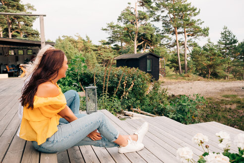 Glückliche junge Frauen sitzen auf der Terrasse eines Ferienhauses - MASF01817