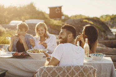 Happy friends enjoying lunch at table on jetty - MASF01821