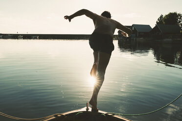 Hemdloser Mann in voller Länge, der an einem sonnigen Tag vom Boot aus in den See taucht - MASF01824