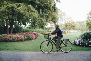 Full length side view of smiling senior woman riding bicycle in park - MASF01834