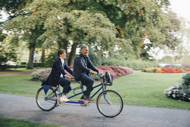 Full length of senior couple enjoying tandem bike ride in park - MASF01835