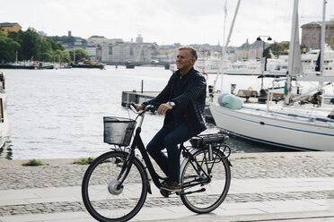 Full length of senior man riding bicycle on road by harbor - MASF01838