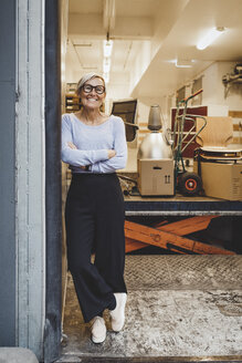 Full length portrait of smiling mature businesswoman standing arms crossed in new office - MASF01846