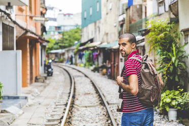 Vietnam, Hanoi, Mann in der Stadt mit Eisenbahnschienen entlang der Häuser - WPEF00210