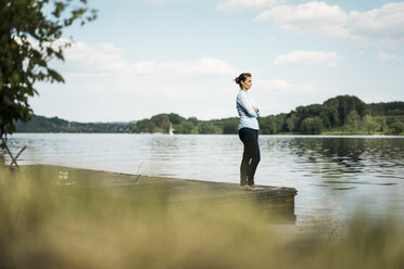 Woman standing on jetty at a lake - JOSF02166