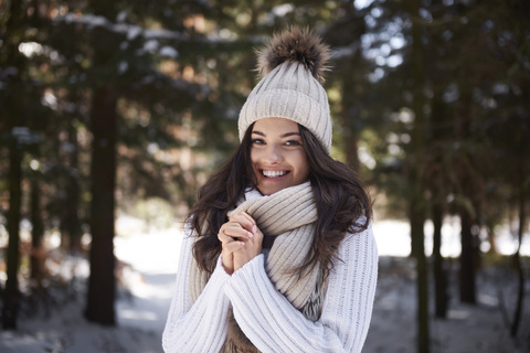 Portrait of happy young woman wearing knitwear in winter forest stock photo