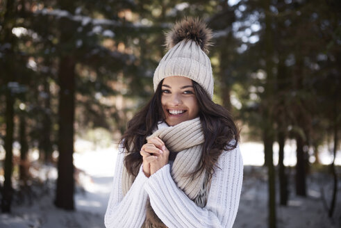 Porträt einer glücklichen jungen Frau in Strickwaren im Winterwald - ABIF00278