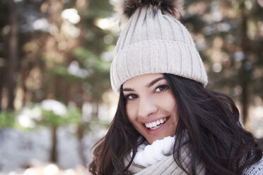 Portrait of smiling young woman wearing woolly cap in forest - ABIF00281