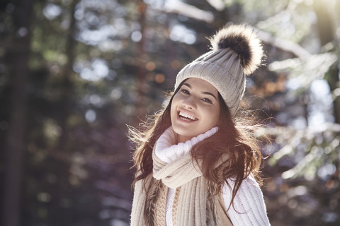 Portrait of laughing young woman wearing knitwear in winter forest stock photo