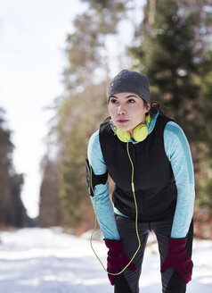 Junge Joggerin im Winterwald macht eine Pause - ABIF00293