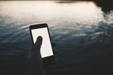 Ausgeschnittenes Bild eines Mannes, der sein Smartphone am See benutzt - MASF01868