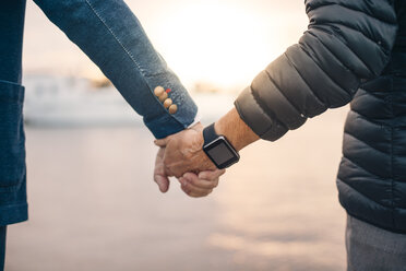 Ausgeschnittenes Bild einer älteren Frau, die eine intelligente Uhr trägt, während sie die Hand eines Mannes im Hafen hält - MASF01875