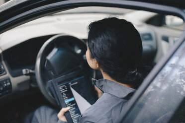 Female mechanic using digital tablet while sitting in car - MASF01884