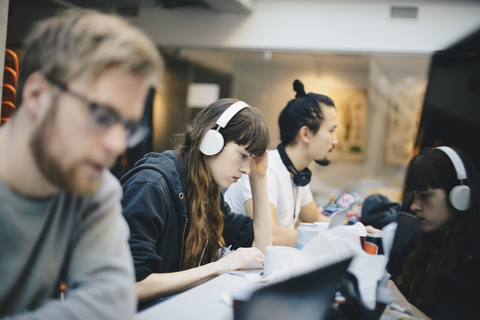 Weibliche Programmiererin arbeitet am Computer mit männlichen Kollegen am Schreibtisch im Büro, lizenzfreies Stockfoto