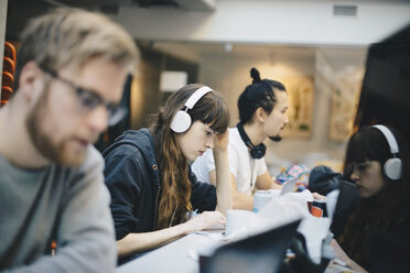 Weibliche Programmiererin arbeitet am Computer mit männlichen Kollegen am Schreibtisch im Büro - MASF01889