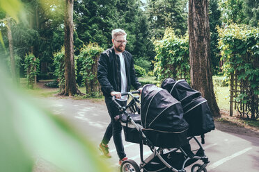 Mann, der einen Kinderwagen auf dem Fußweg schiebt, in voller Länge - MASF01901