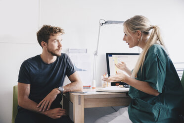 Eine Krankenschwester erklärt einem jungen männlichen Patienten im Büro eines Krankenhauses etwas - MASF01902