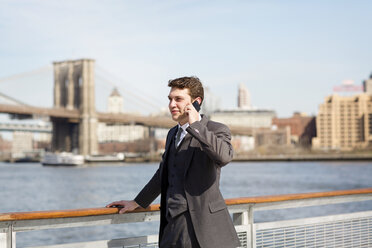 Geschäftsmann, der mit seinem Smartphone telefoniert, während er an einem Brückengeländer steht - CAVF35406