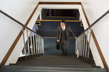 Geschäftsmann steigt in der Lobby eines Restaurants die Treppe hinauf - CAVF35409