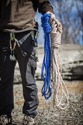 Low section man holding climbing ropes while standing on field - CAVF35431