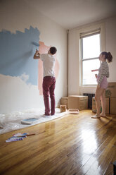 Woman looking at boyfriend painting on wall - CAVF35436