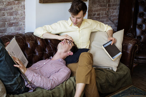 Zärtliches schwules Paar entspannt sich auf dem Sofa zu Hause - CAVF35459