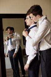 Seitenansicht eines schwulen Mannes, der seinem Freund beim Binden einer Krawatte hilft - CAVF35470