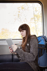 Frau benutzt Tablet-Computer im Zug sitzend - CAVF35489