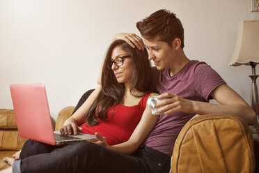 Lesbisches Paar, das einen Laptop benutzt, während es sich zu Hause entspannt - CAVF35507