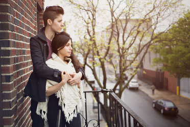 Lesbian couple looking away while standing in balcony - CAVF35516