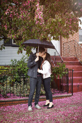 Lesbisches Paar, das sich küsst, während es auf der Straße vor einem Gebäude steht - CAVF35519