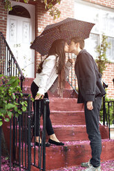 Affectionate lesbian couple kissing while standing on steps against building - CAVF35521