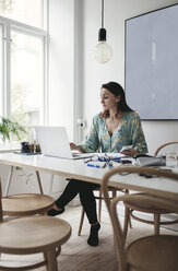 Businesswoman using laptop on table in home office - MASF01946