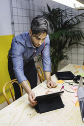Junger Mann mit digitalem Tablet am Schreibtisch im Kreativbüro - MASF01964