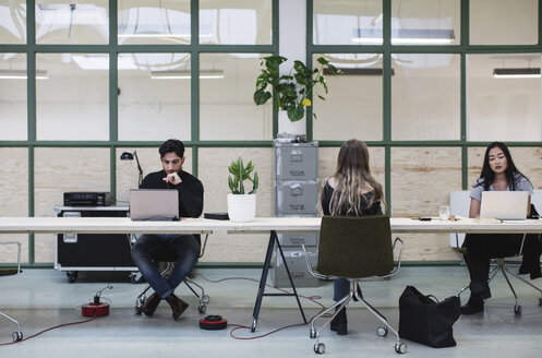 Two women and one man working at desk in creative office - MASF01971