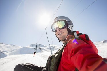 Smiling man in ski-wear on snow covered field against clear sky - MASF02008