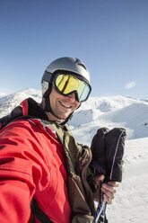 Lächelnder Mann in Skikleidung auf einem schneebedeckten Feld vor klarem Himmel - MASF02009